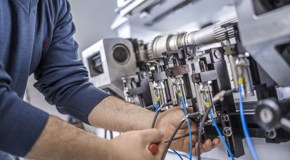 Close up of service technician performing industrial machinery inspection and repair on electrical components