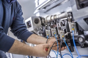 Close up of service technician performing industrial machinery inspection and repair on electrical components