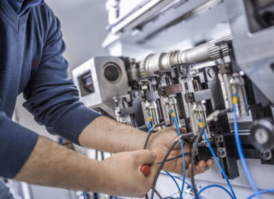 Close up of service technician performing industrial machinery inspection and repair on electrical components